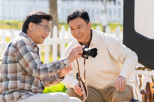 两个老年男人坐在露营地看数码相机图片