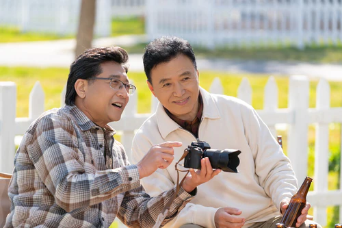 两个老年男人坐在露营地看数码相机图片