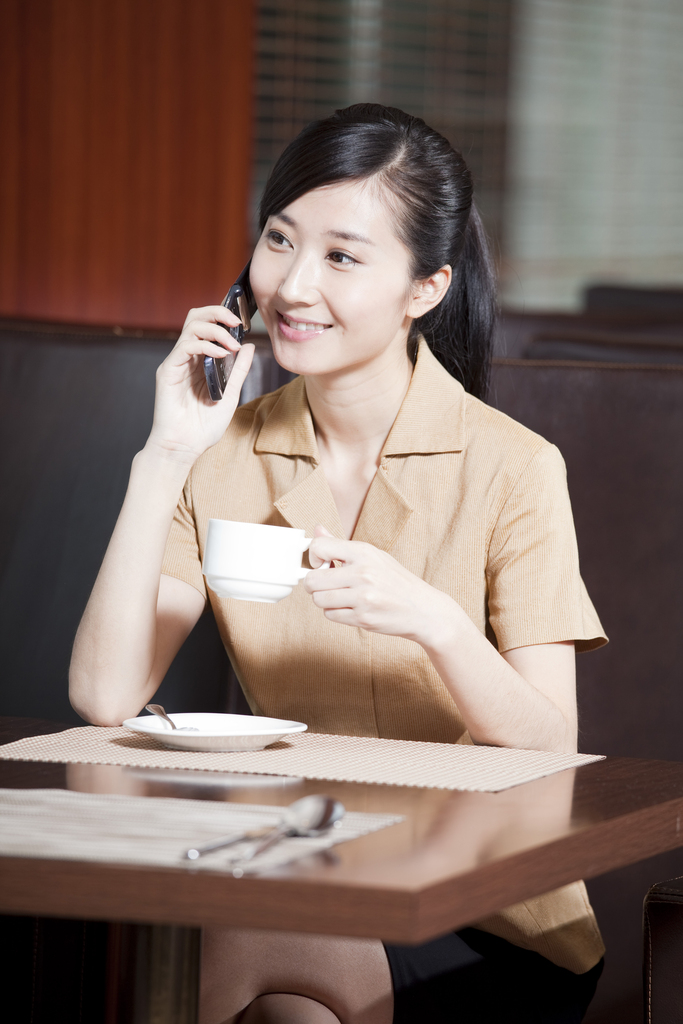 端着咖啡杯的商务女士正在打手机