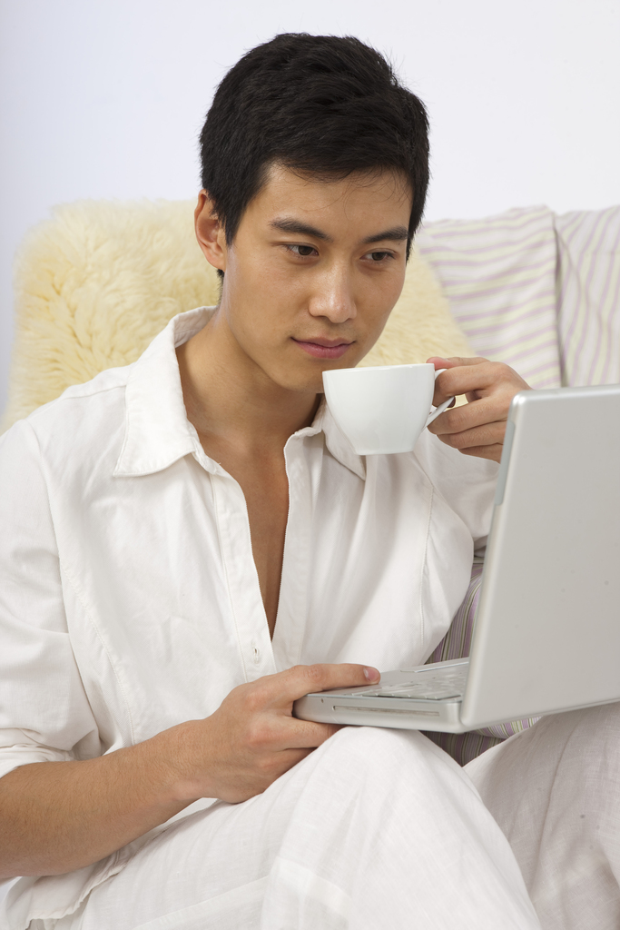 年轻男人边喝咖啡边看笔记本电脑图片