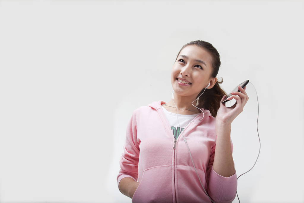 快乐的年轻女人使用手机听音乐图片