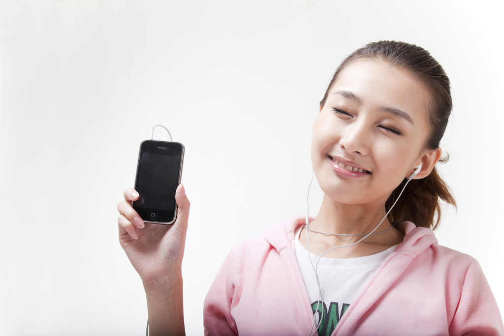 快乐的年轻女人使用手机听音乐图片