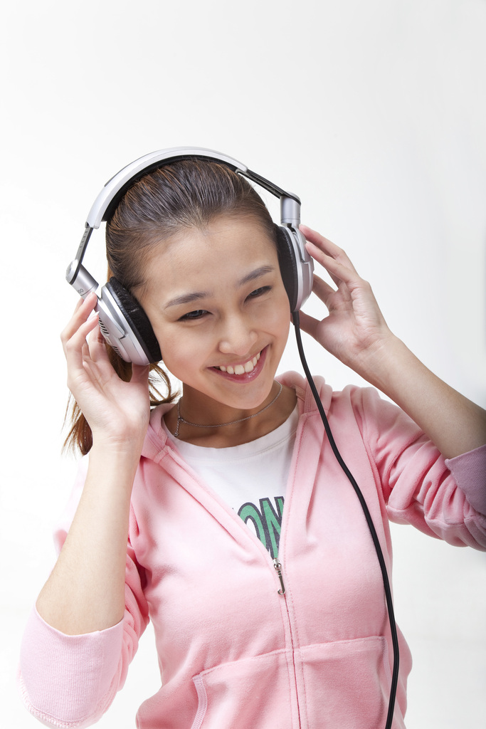 快乐的年轻女人戴耳机听音乐