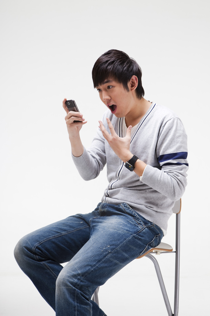 年轻男人做在椅子上使用手机图片