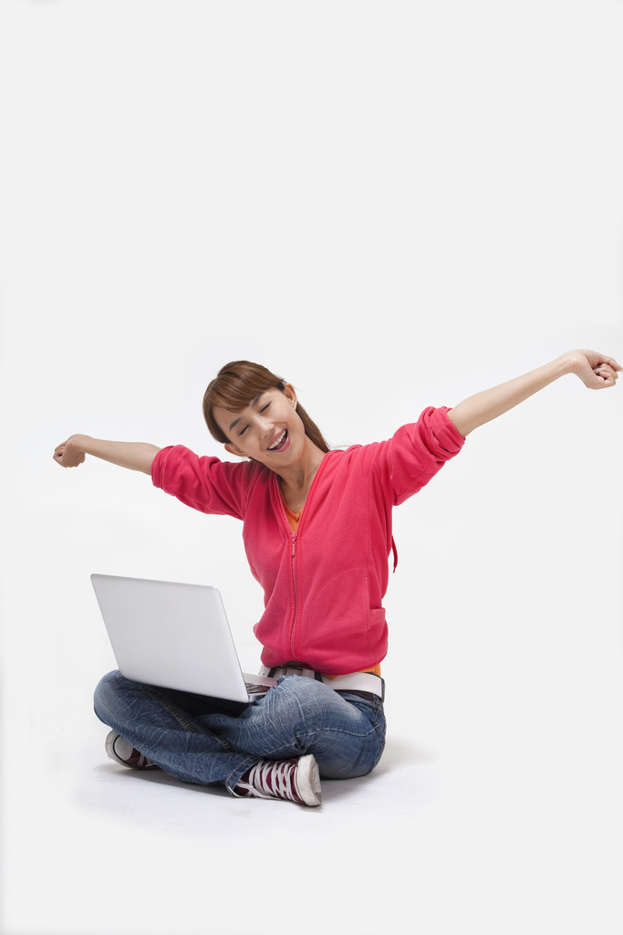 年轻女人坐在地上使用笔记本电脑图片