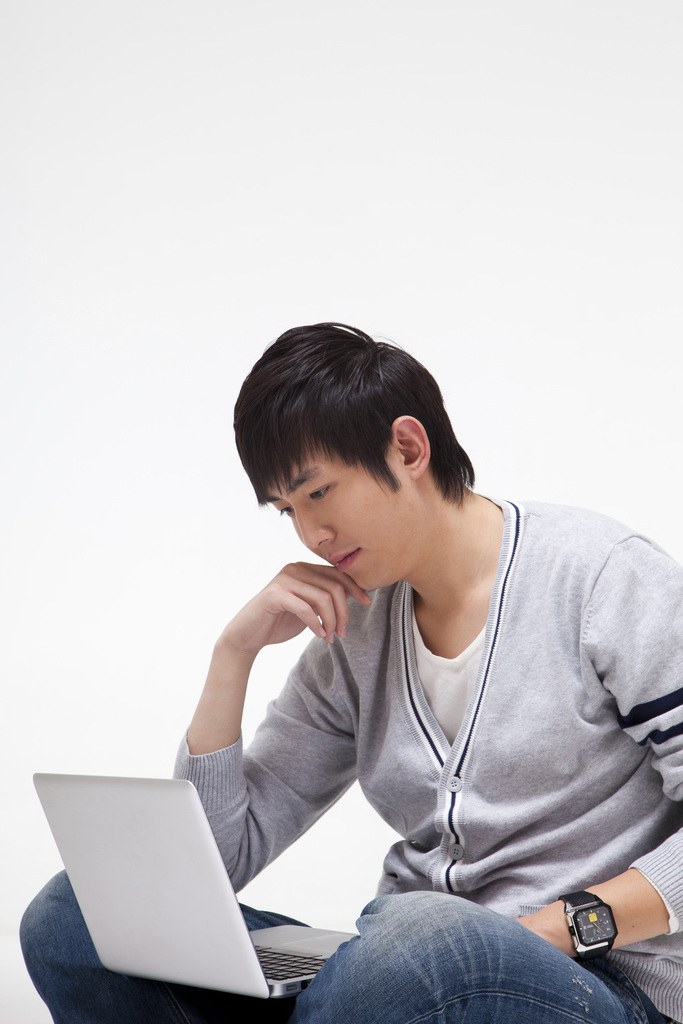 年轻男人坐在地上使用笔记本电脑