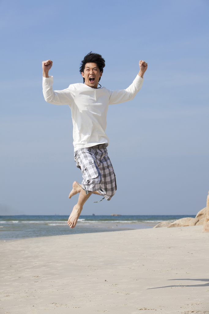 海边休闲装年轻男人跳跃