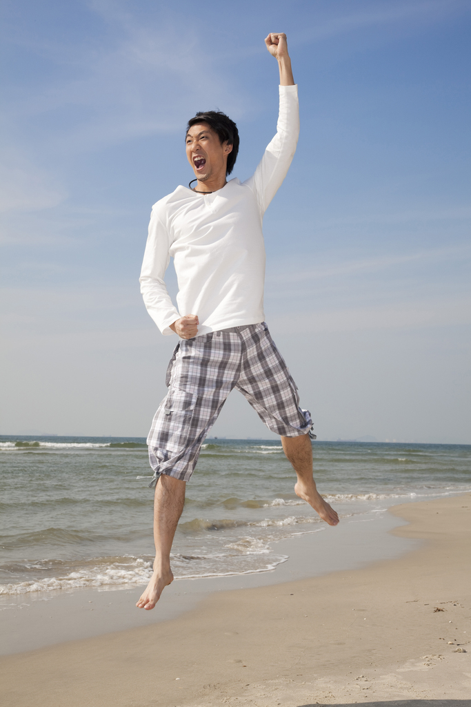 海边休闲装年轻男人跳跃