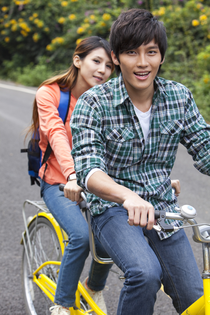 年轻大学生情侣在校园里骑车