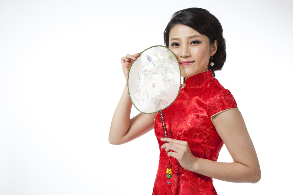 棚拍节日身穿红色旗袍的年轻女人拿着扇子