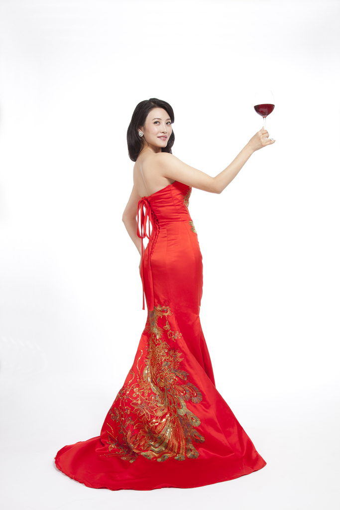 棚拍穿红色礼服的年轻女人端着红酒杯