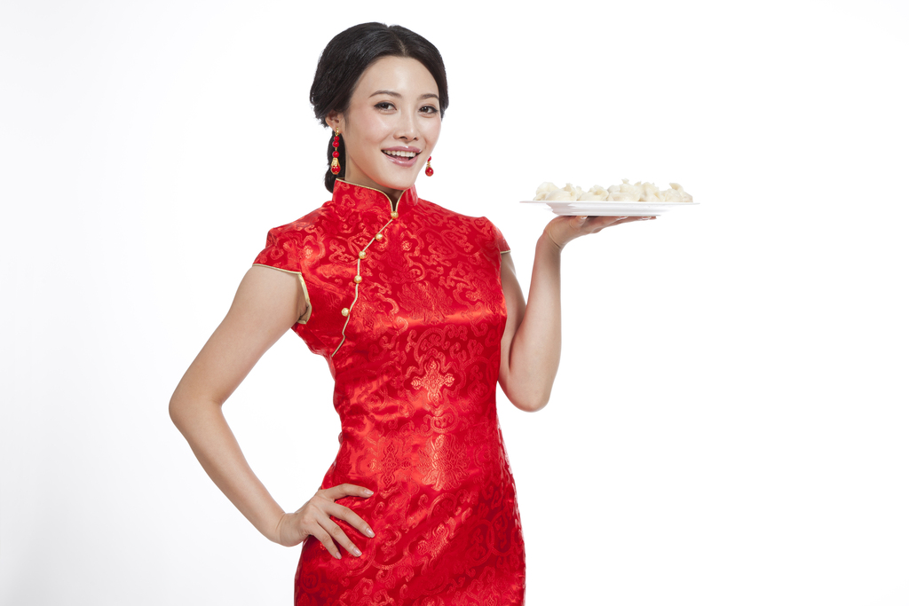 棚拍节日身穿红色旗袍的年轻女人端着饺子图片