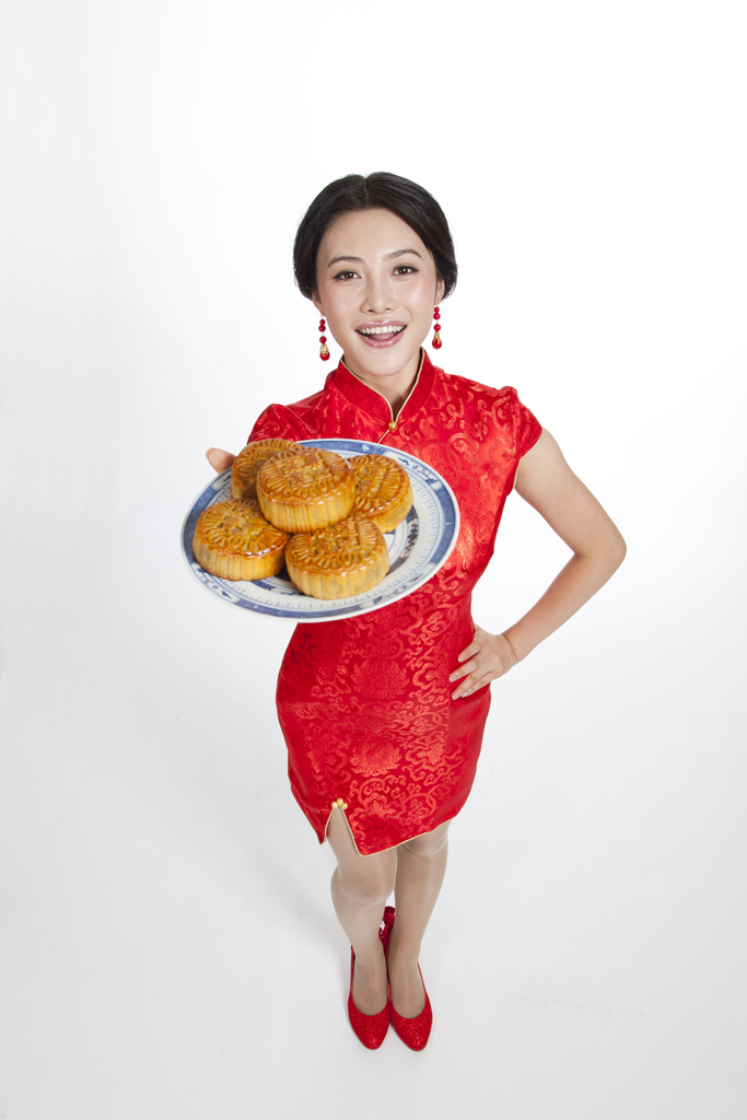 棚拍节日身穿红色旗袍的年轻女人端着月饼图片
