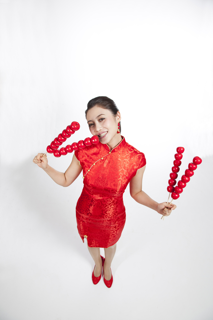 棚拍节日身穿红色旗袍的年轻女人拿着糖葫芦