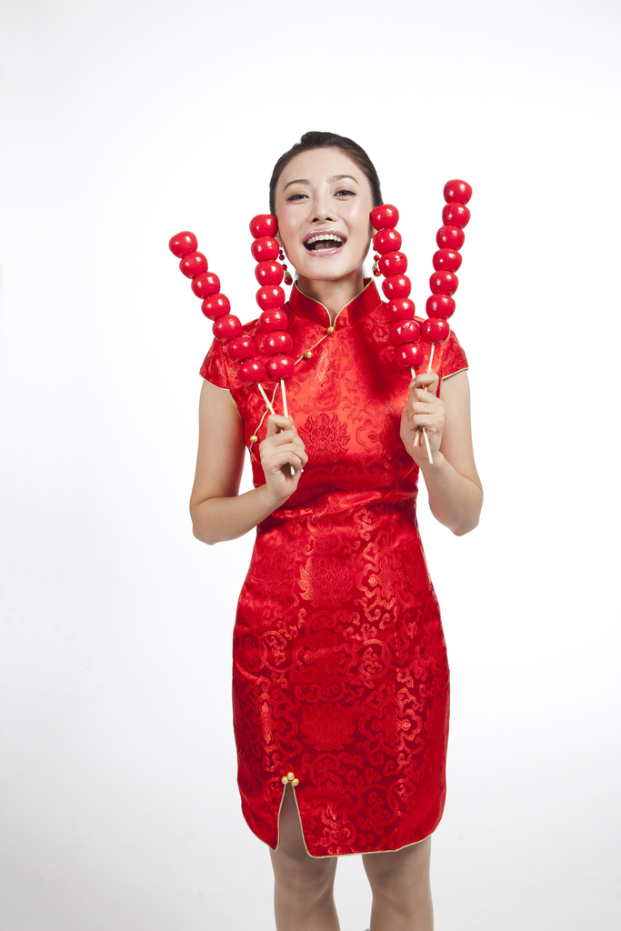 棚拍节日身穿红色旗袍的年轻女人拿着糖葫芦