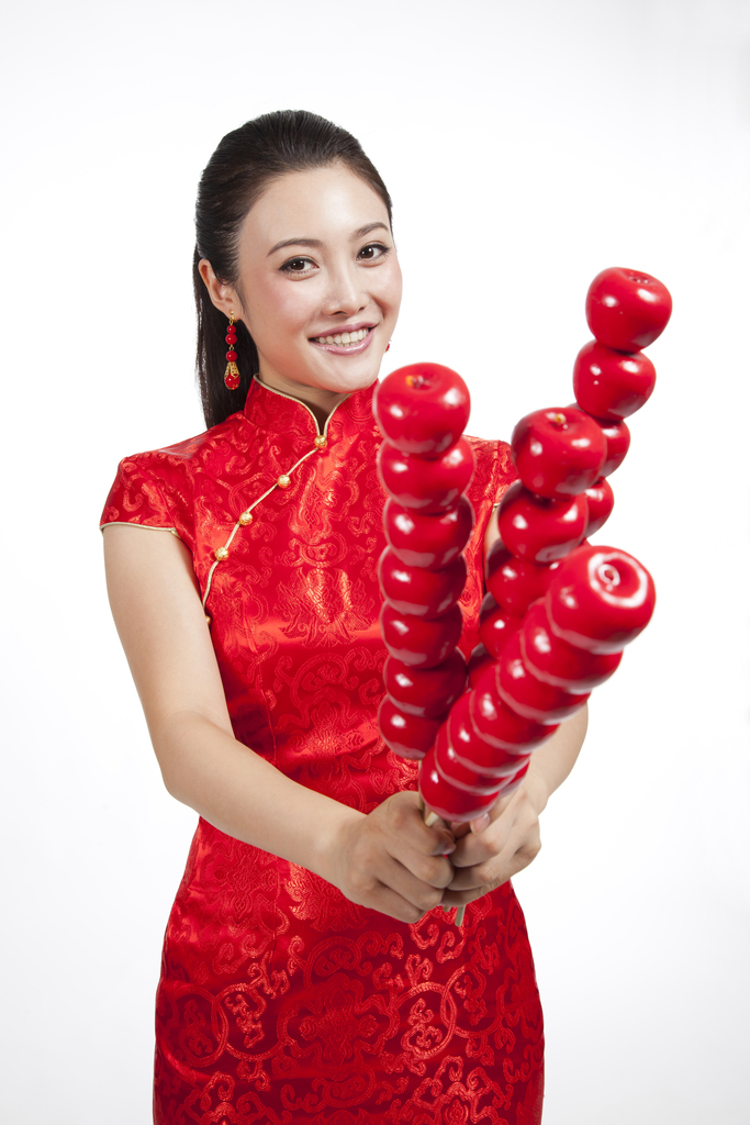 棚拍节日身穿红色旗袍的年轻女人拿着糖葫芦