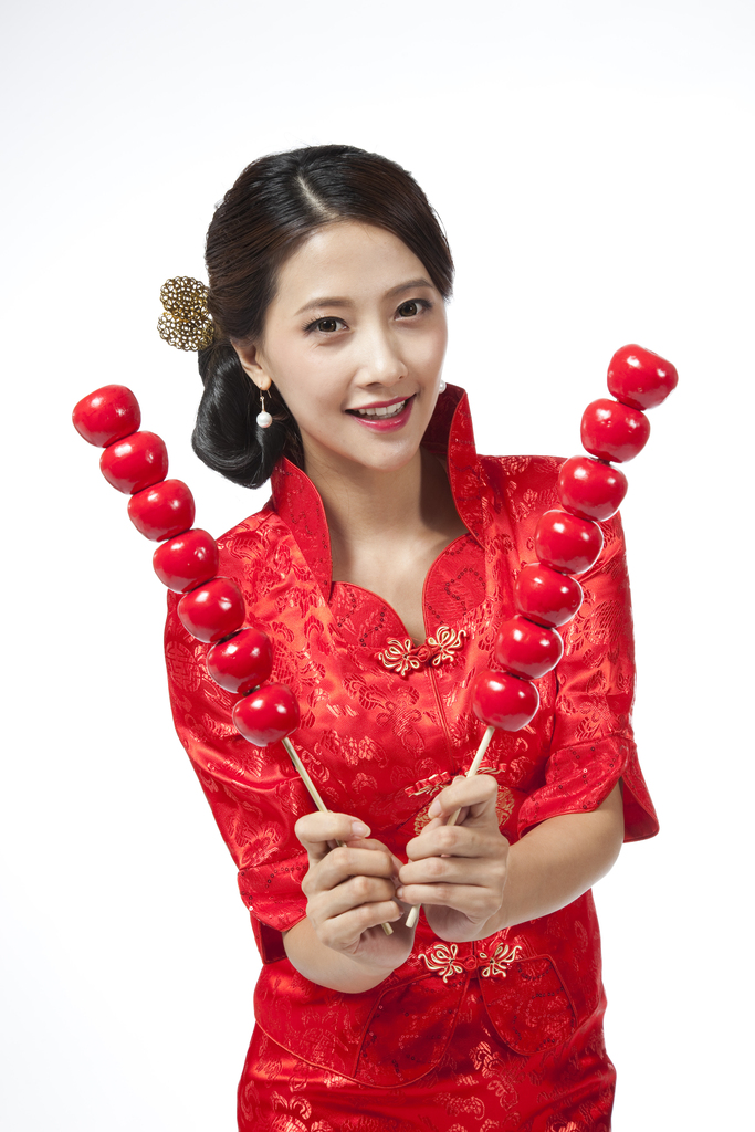 棚拍身穿红色旗袍的年轻女人拿着糖葫芦