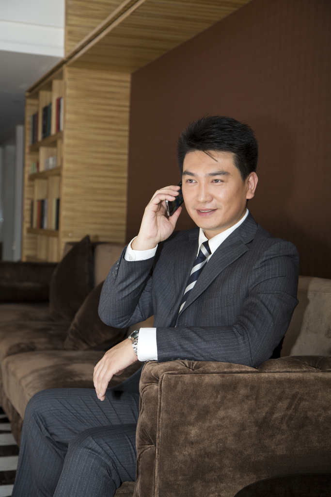 中年商务男士坐在沙发上打手机图片