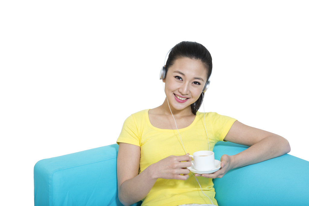 棚拍年轻女人坐在沙发上听着音乐喝咖啡图片