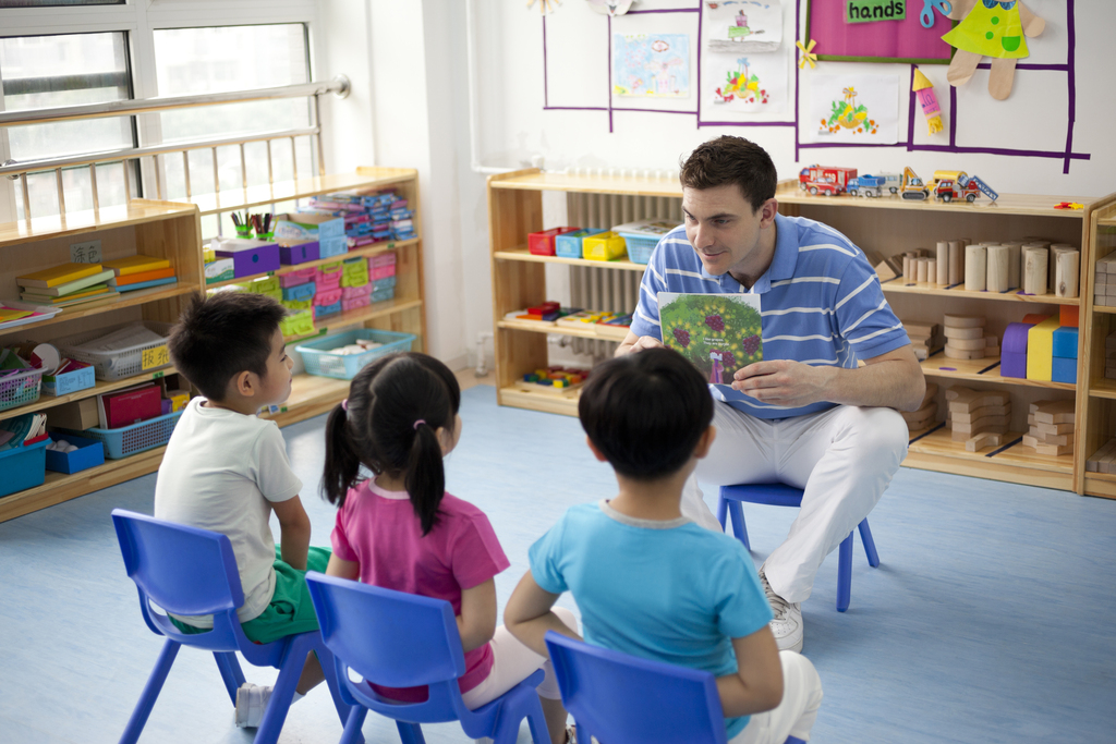 幼儿园外教男老师和小朋友们一起看画册图片