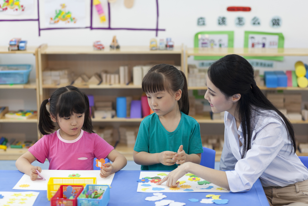 幼儿园女老师辅导儿童做手工