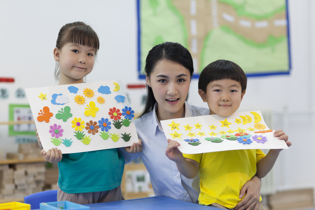 幼儿园女老师辅导儿童做手工