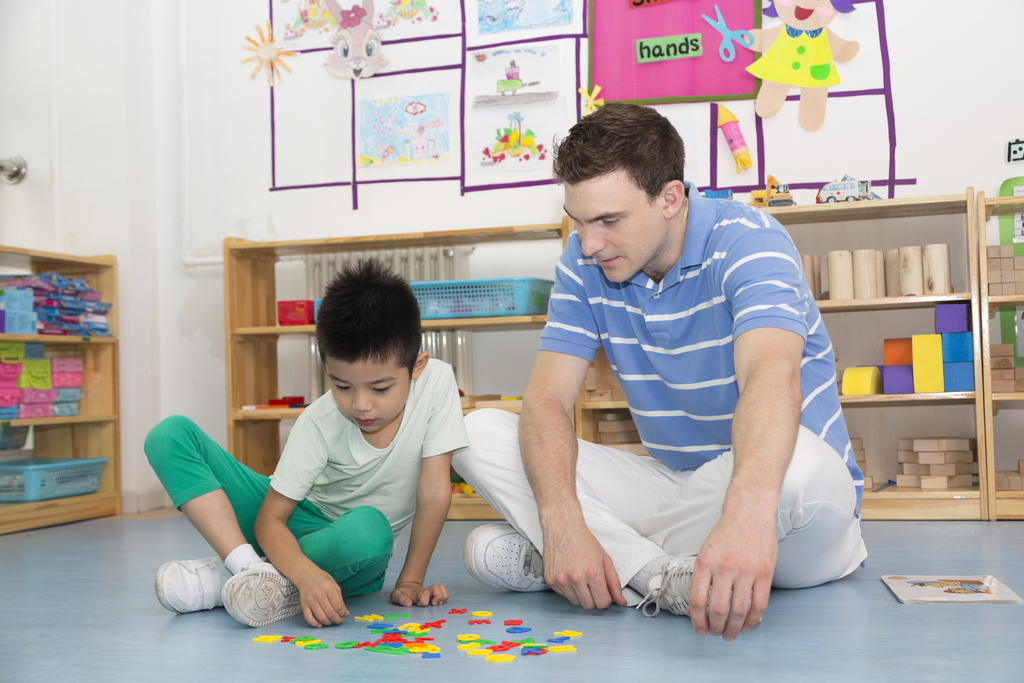 幼儿园外教男老师和儿童一起玩字母游戏