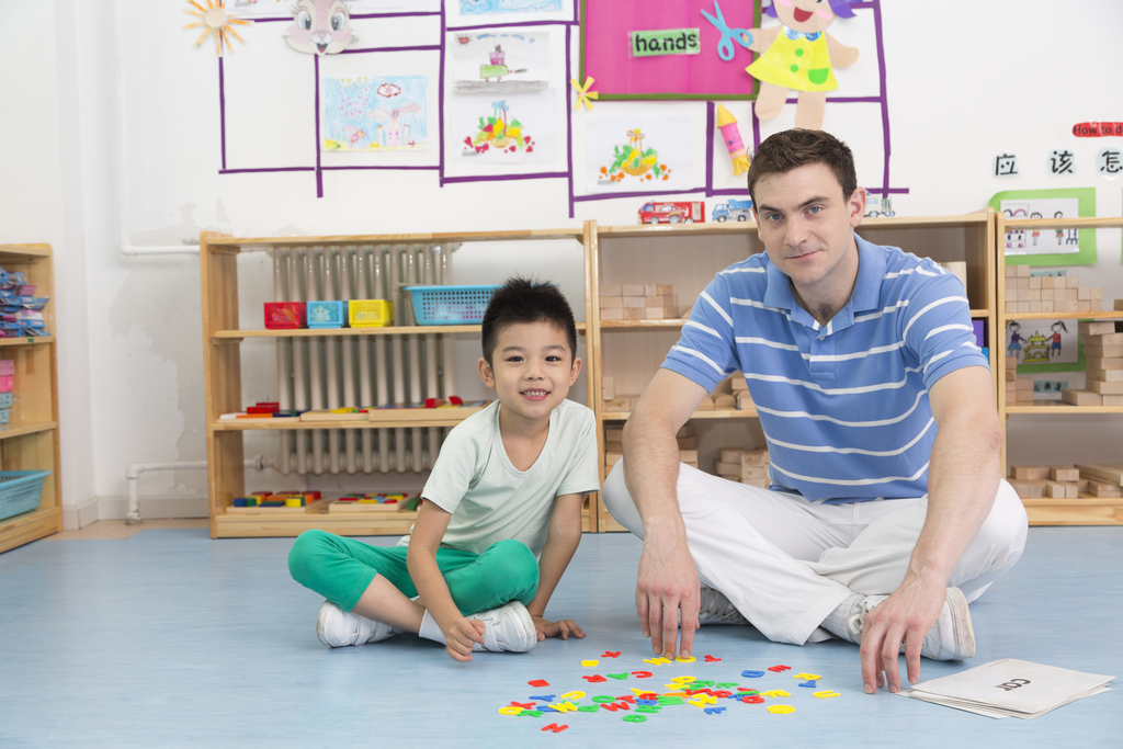 幼儿园外教男老师和儿童一起玩字母游戏