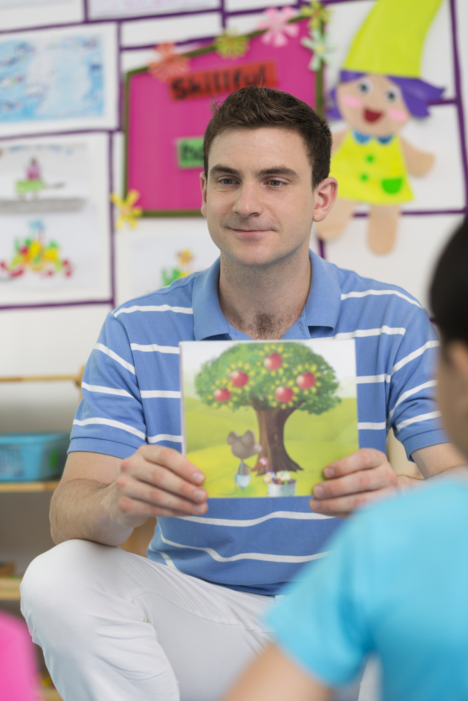 幼儿园外教男老师和儿童一起看画册图片