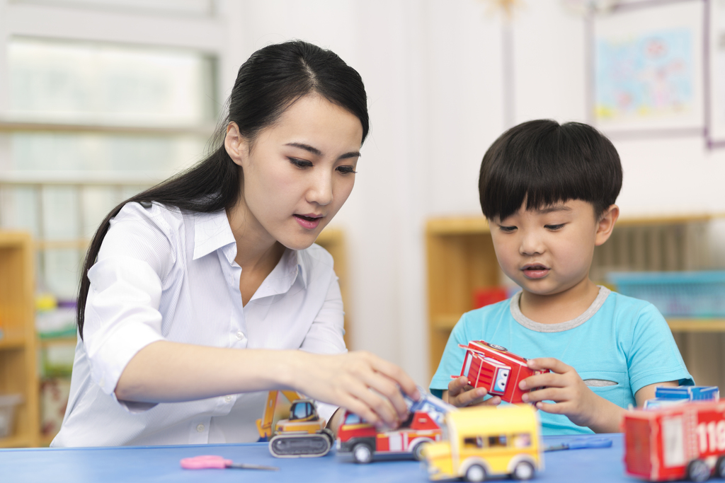 幼儿园女老师和儿童一起玩小汽车玩具