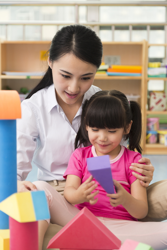 幼儿园女老师和儿童坐在地板上一起玩彩色积木图片