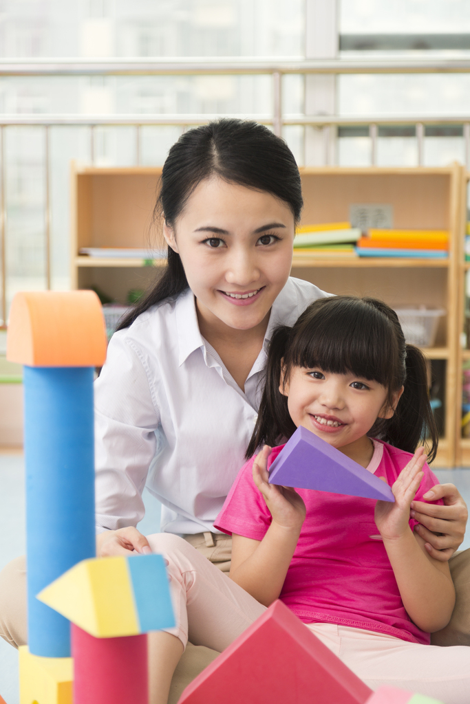 幼儿园女老师和儿童坐在地板上一起玩彩色积木图片