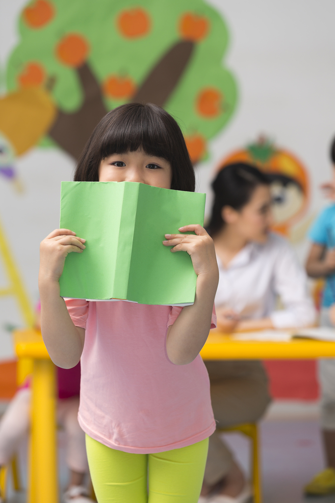 幼儿园儿童拿书本挡住脸微笑图片