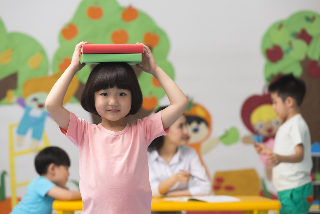 幼儿园儿童头顶着书本微笑图片