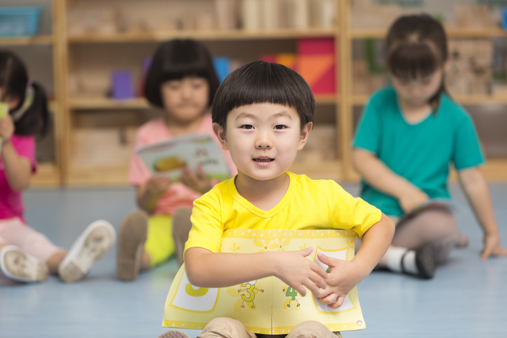 幼儿园儿童坐在地板上看故事书