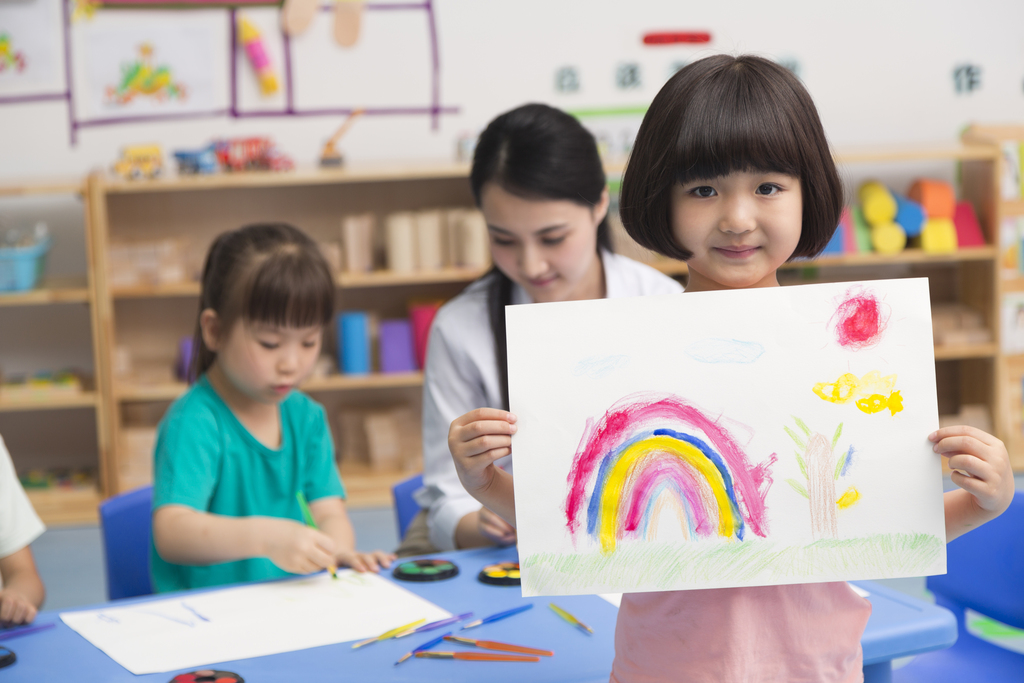 幼儿园女老师和儿童展示绘画作品