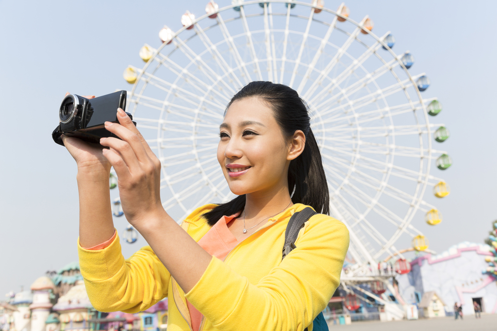 年轻女人手拿DV在游乐园图片