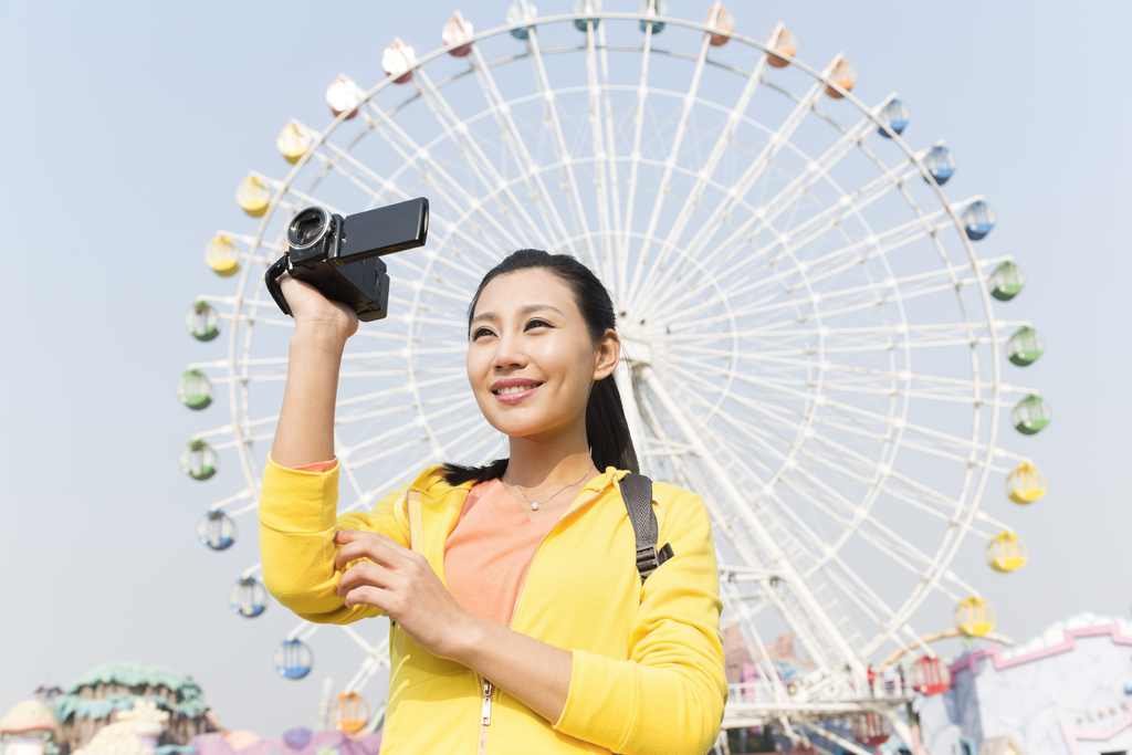 年轻女人手拿DV在游乐园图片