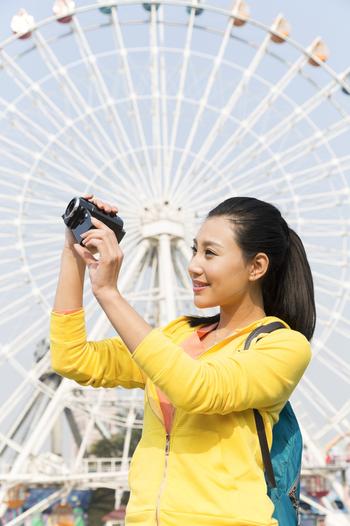 年轻女人手拿DV在游乐园图片