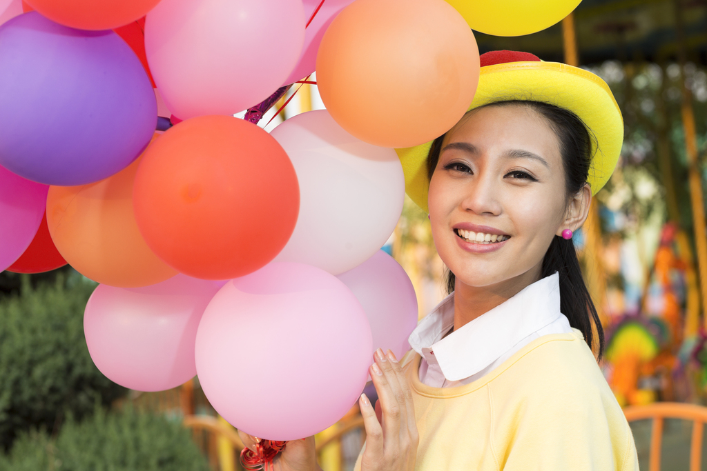 年轻女人牵着气球在游乐园图片