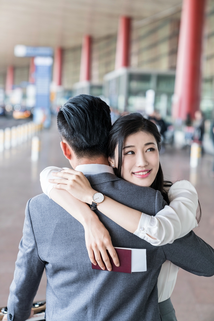 年轻情侣在机场团聚拥抱
