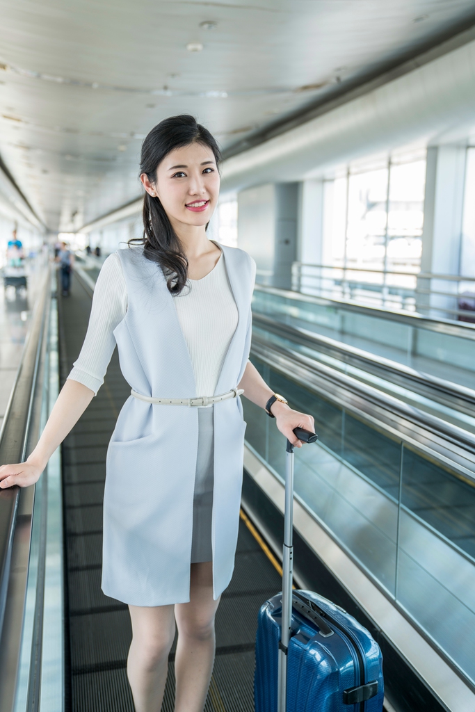 年轻商务女士在机场乘坐移动电梯