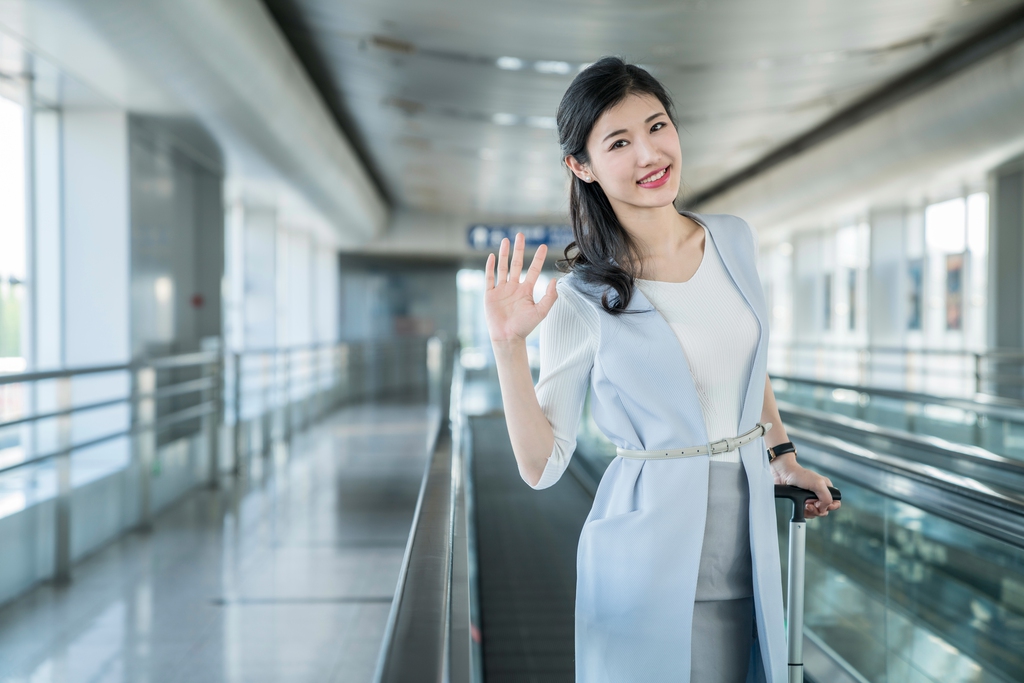 年轻商务女士在机场乘坐移动电梯图片