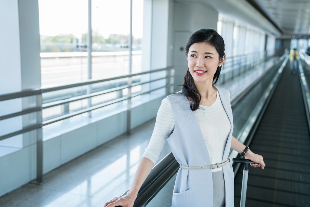 年轻商务女士在机场乘坐移动电梯