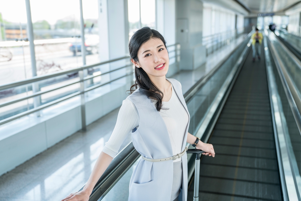 年轻商务女士在机场乘坐移动电梯图片