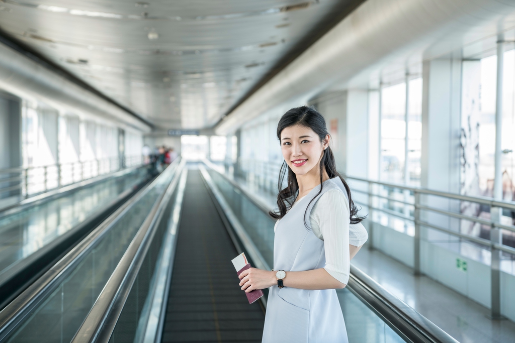 年轻商务女士在机场乘坐移动电梯图片