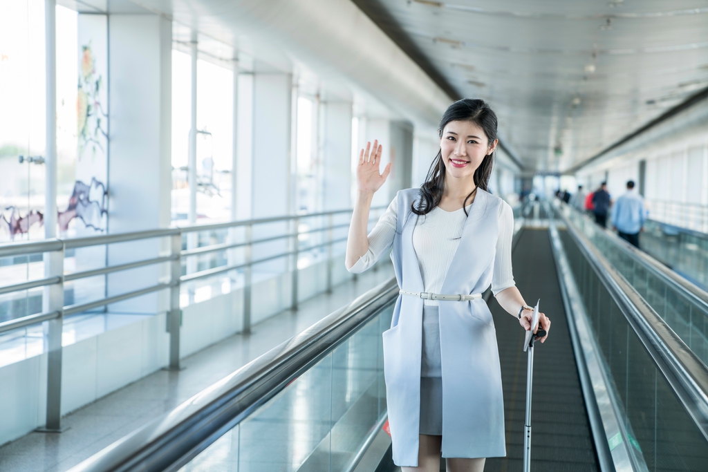 年轻商务女士在机场乘坐移动电梯图片