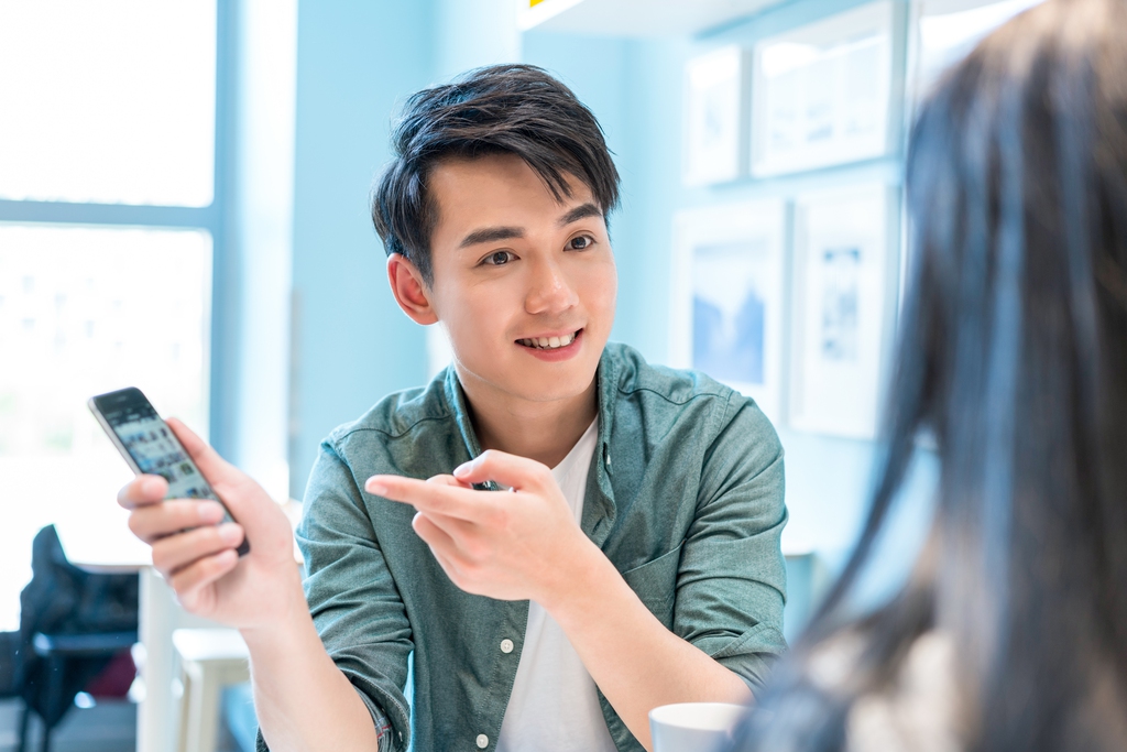 年轻男子向朋友展示手机