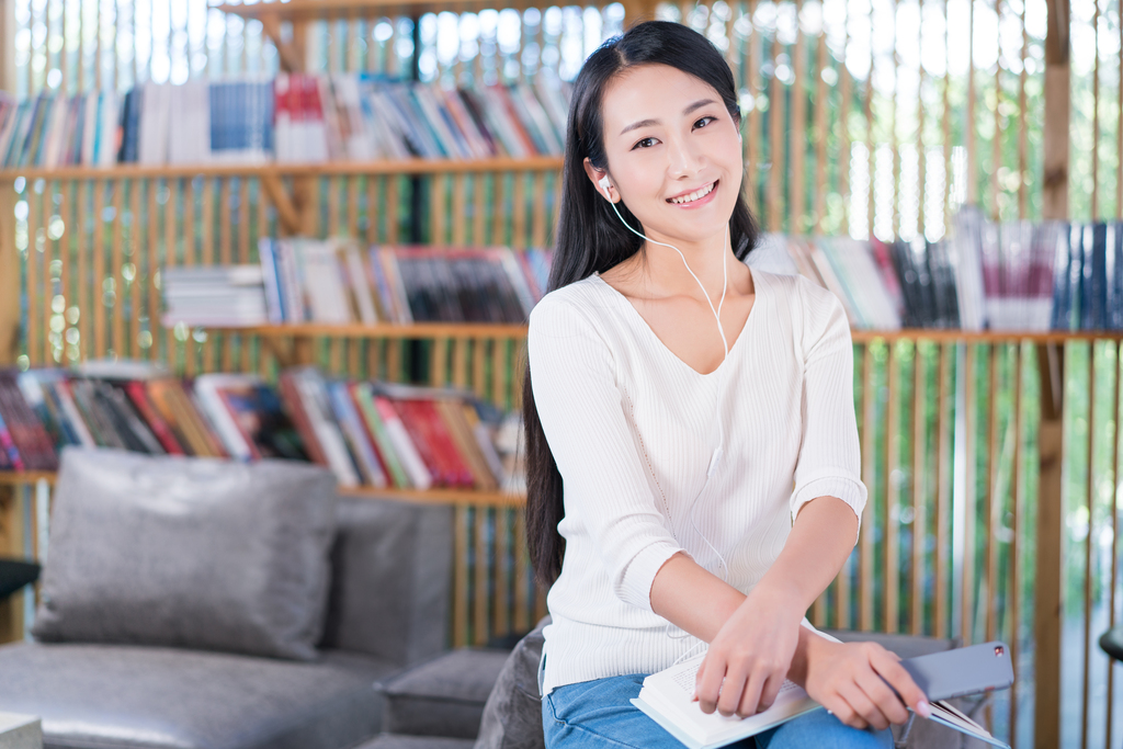 年轻女子在书店看书听音乐