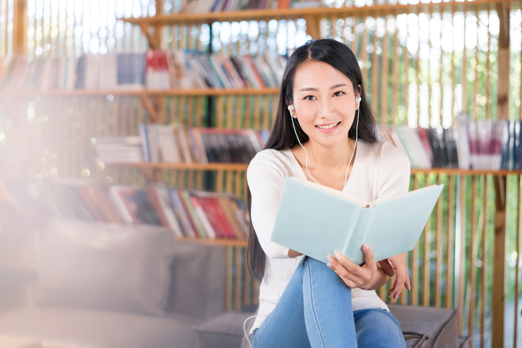 年轻女子在书店看书听音乐图片